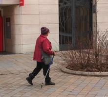 nitra, slovacchia - 01.06.2023 un' maturo donna con nordico a piedi bastoni passeggiate attraverso il città strade. il concetto di un' salutare stile di vita. foto
