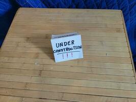 carta sotto costruzione cartello su Marrone legna tavolo foto