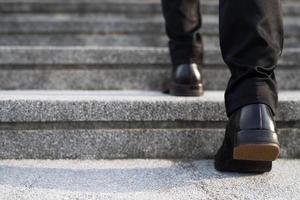 moderno uomo d'affari Lavorando avvicinamento gambe a piedi su il le scale nel moderno città. nel corsa ora per opera nel ufficio un' fretta foto