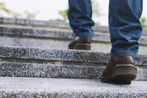 moderno uomo d'affari Lavorando avvicinamento gambe a piedi su il le scale nel moderno città. nel corsa ora per opera nel ufficio un' fretta foto