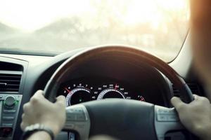 primo piano delle mani tenere il volante giovane uomo alla guida di un'auto che guida sulla strada. viaggio dell'autista di viaggio. foto