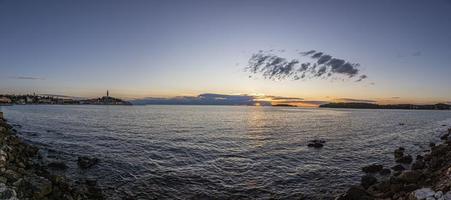 Visualizza per il storico centro di rovigno durante tramonto con acqua riflessi e simpatico nube formazioni foto