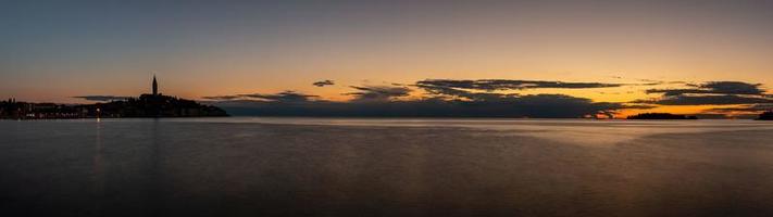 Visualizza per il storico centro di rovigno durante tramonto con acqua riflessi e simpatico nube formazioni foto