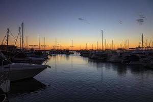 Immagine di yachts nel marina dopo tramonto con acqua riflessi foto