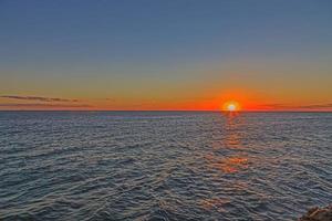 immagine di un' tramonto al di sopra di il mare prese a il momento quando il sole scomparso su il orizzonte foto