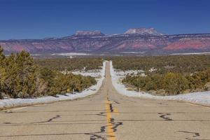 panoramico Visualizza lungo vuoto e infinito strada con orsi orecchie montagne nel il sfondo nel inverno foto