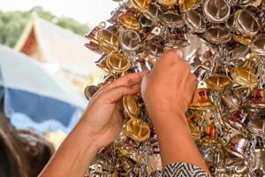 vicino su mano afferrare piccolo d'oro e argento campane per sospeso nel tailandese tempio. foto