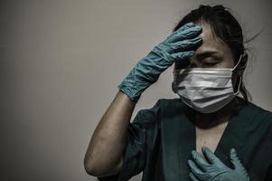 stanco depresso donna asiatica scrub infermiera indossa maschera facciale uniforme blu siede sul pavimento dell'ospedale, giovane donna medico stressato dal duro lavoro foto