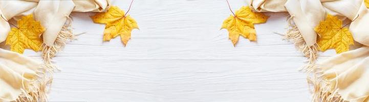 autunno le foglie con un' sciarpa su un' di legno sfondo con copia spazio. bandiera foto