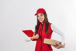 consegna persona consegna pacchi Tenere appunti e pacchetto sorridente contento nel rosso uniforme. bellissimo giovane donna professionale Corriere isolato su bianca sfondo foto