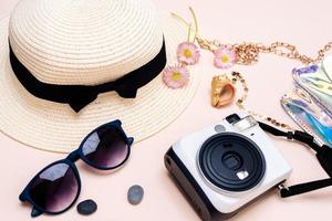 estate viaggio Accessori. telecamera, cappello, bicchieri e un' piatto bloc notes superiore Visualizza posare piatto su un' leggero sfondo foto