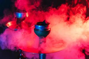 narghilè ciotola, shisha e carboni avvicinamento su un' fumoso nero sfondo con colorato illuminazione foto