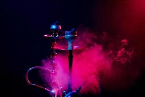 narghilè ciotola, shisha e carboni su un' fumoso nero sfondo con colorato illuminazione foto