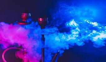 moderno narghilè, shisha su un' fumoso nero sfondo con colorato illuminazione e Fumo. avvicinamento e posto per il tuo testo foto