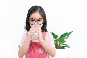 bambino Asia ragazza bevanda latte con un' bicchiere foto