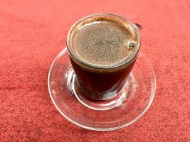 un' tazza di nero caffè su il rosso tappeto foto