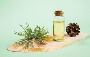 essenziale pino olio nel bicchiere bottiglia su di legno sega tagliare su menta verde sfondo. foto