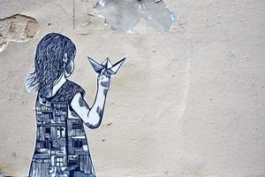 montmartre, francia, 2020 - arte di strada di una ragazza che tiene una barchetta di carta foto