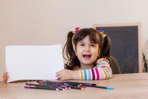 un' carino poco ragazza nel un' disegno lezione detiene un vuoto bianca foglio nel sua mani, un' spazio per testo. bambini e creatività. alto qualità foto