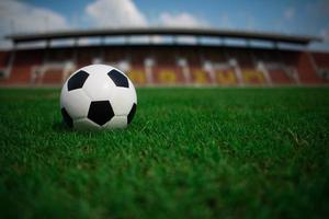 un pallone da calcio in erba con sfondo stadio foto