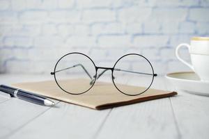 blocco note, occhiali e una matita sul tavolo di legno foto