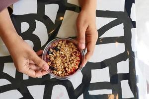 superiore Visualizza di donne Tenere un' ciotola di prima colazione cereale su tavolo foto