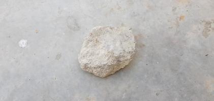avvicinamento Visualizza di un' singolo pietra isolato su grigio cemento superficie foto