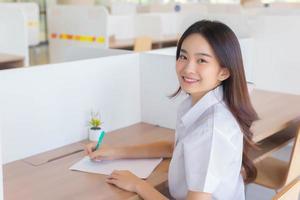 ritratto di adulto tailandese alunno. bellissimo asiatico giovane donna alunno nel uniforme è sorridente e guardare a telecamera nel il aula a Università. foto