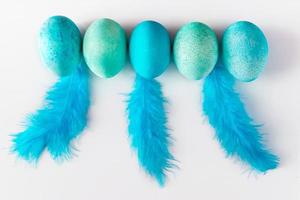 belle uova di Pasqua blu e piume su sfondo chiaro. foto