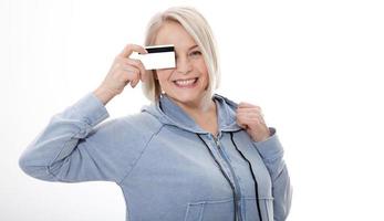 contento anziano donna Tenere e mostrando credito carta al di sopra di bianca sfondo foto