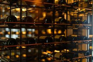 molti bicchiere vino bottiglie su vino scaffali con illuminazione. interno nel il ristorante. colore foto