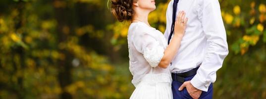 Novelli sposi sposo e sposa a piedi nel autunno parco foto