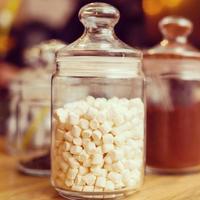 mucchio di marshmallows nel trasparente bicchiere vaso su leggero rosa stoffa sfondo foto