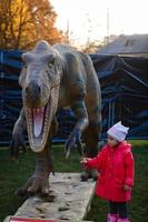poco ragazza e grande dinosauro foto