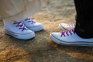 amore storia detto di stivali. umano piedi vicino su. uomo e donna nel scarpe da ginnastica. ragazza nel bianca scarpe. tipo nel nero scarpe da ginnastica e denim. fricchettone coppia nel estate. gambe vicino su. foto