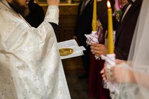 bellissima sposa e elegante sposo Tenere candele a ufficiale nozze cerimonia nel vecchio Chiesa. tradizionale momento foto