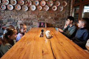 quattro bambini sedersi nel autentico ucraino ristorante, guardare su telefoni. foto
