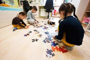 bambini collegamento sega puzzle pezzi nel un' bambini camera su pavimento a casa. divertimento famiglia attività tempo libero. foto