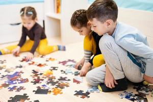 bambini collegamento sega puzzle pezzi nel un' bambini camera su pavimento a casa. divertimento famiglia attività tempo libero. foto