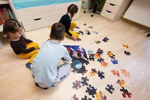 bambini collegamento sega puzzle pezzi nel un' bambini camera su pavimento a casa. divertimento famiglia attività tempo libero. foto