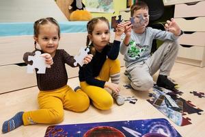 bambini collegamento sega puzzle pezzi nel un' bambini camera su pavimento a casa. divertimento famiglia attività tempo libero. foto