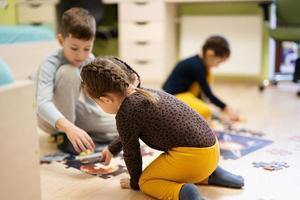 bambini collegamento sega puzzle pezzi nel un' bambini camera su pavimento a casa. divertimento famiglia attività tempo libero. foto