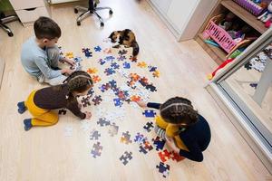 bambini collegamento sega puzzle pezzi nel un' bambini camera su pavimento a casa. divertimento famiglia attività tempo libero. foto