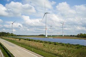 azienda agricola con solare pannelli e vento turbine, collocato Il prossimo per il autostrada, nel il campagna. verde energia concetto. foto