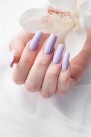 ragazze mani con delicato viola manicure e orchidea fiori foto