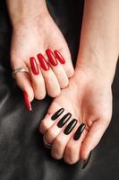 mani di un' giovane ragazza con nero e rosso manicure su Chiodi foto