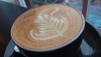 vicino su tiro di capuchino arte nel un' nero caffè tazza foto