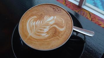 vicino su tiro di capuchino arte nel un' nero caffè tazza foto