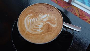 vicino su tiro di capuchino arte nel un' nero caffè tazza foto