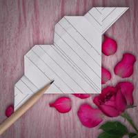 origami carta bianca cuore, matita e rosa rosa fiore su di legno tavolo sfondo foto